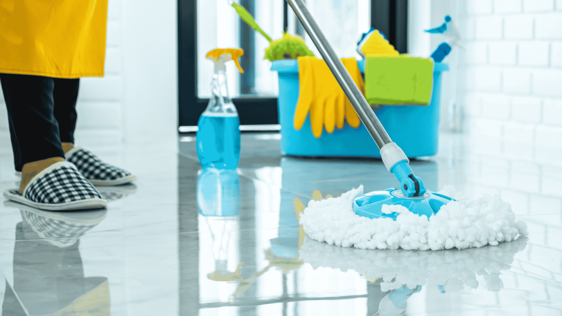 person mopping tile floor with cleaning supplies in background