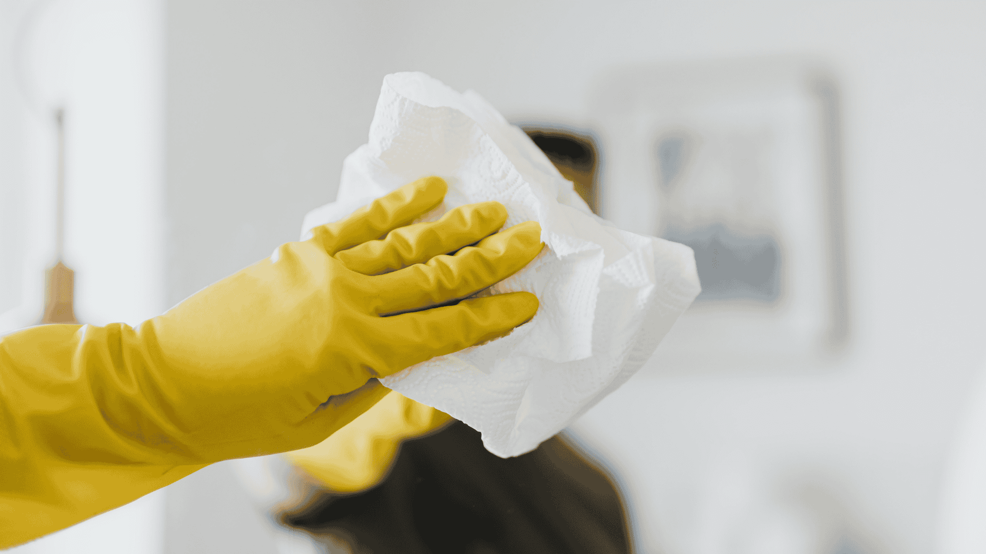 hand wiping surface with cloth and cleaning gloves
